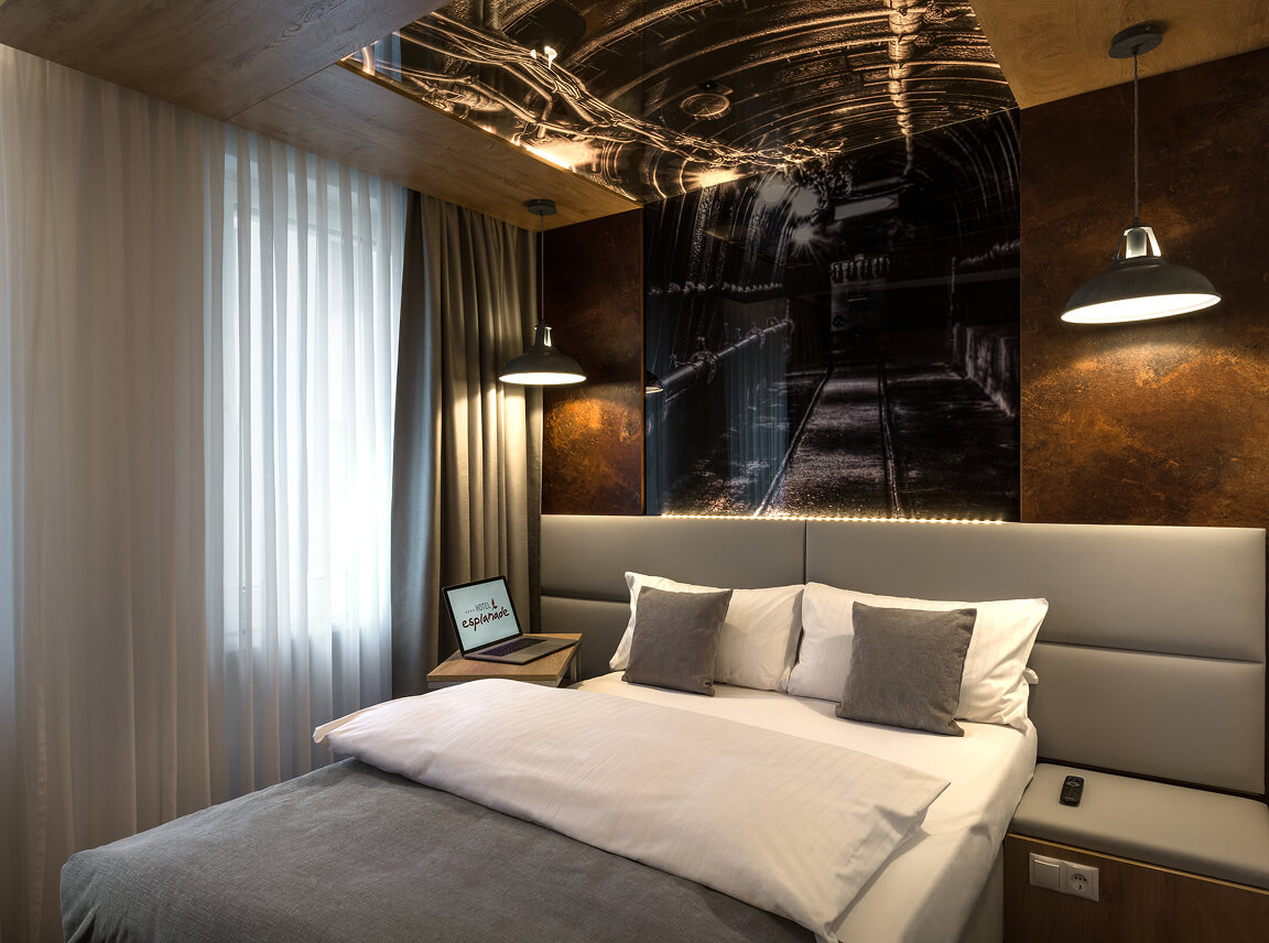 Stylish hotel room with a cosy bed, warm lighting, and an industrial-inspired wall design.