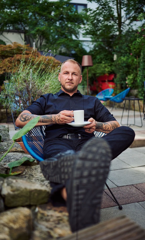A guest relaxing with a cup of coffee in the hotel’s green garden lounge.